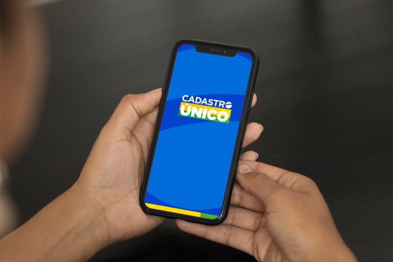 Pessoa segurando smartphone exibindo tela do aplicativo Cadastro Único.