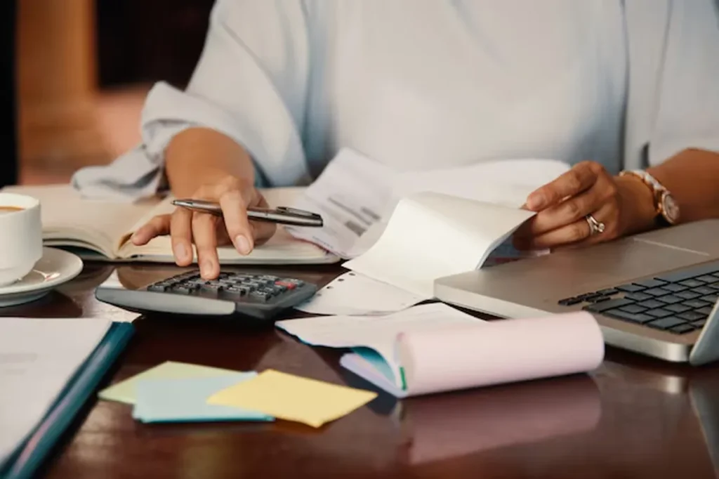 Pessoa usando calculadora e revisando documentos para renegociar dívidas.