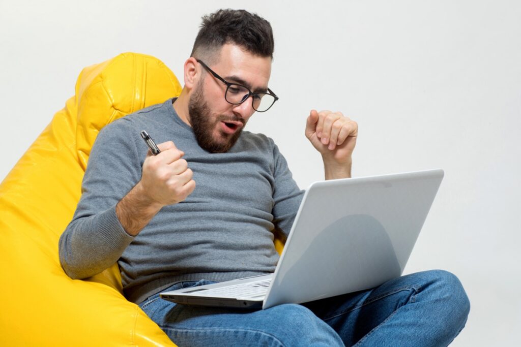 Homem empolgado navegando no laptop descobrindo ofertas e promoções especiais