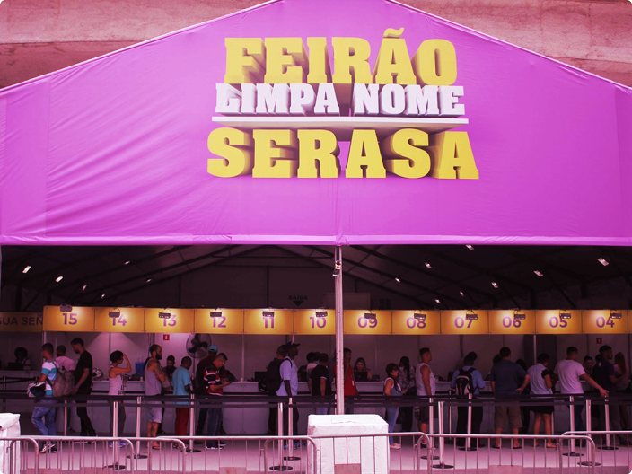 Feirão Serasa Limpa Nome com tenda roxa e fila de consumidores aguardando atendimento presencial para negociação de débitos