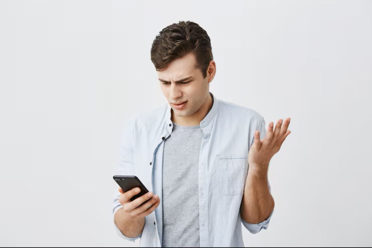 Homem confuso olhando para o celular tentando entender algo