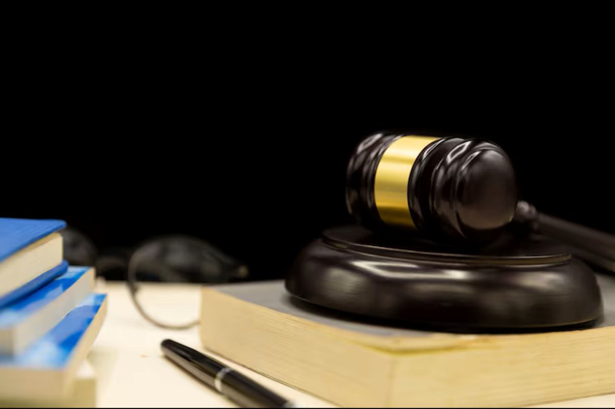 Martelo de juiz sobre livros de direito, com caneta e óculos ao lado, simbolizando a cobrança judicial de dívidas e o processo legal.