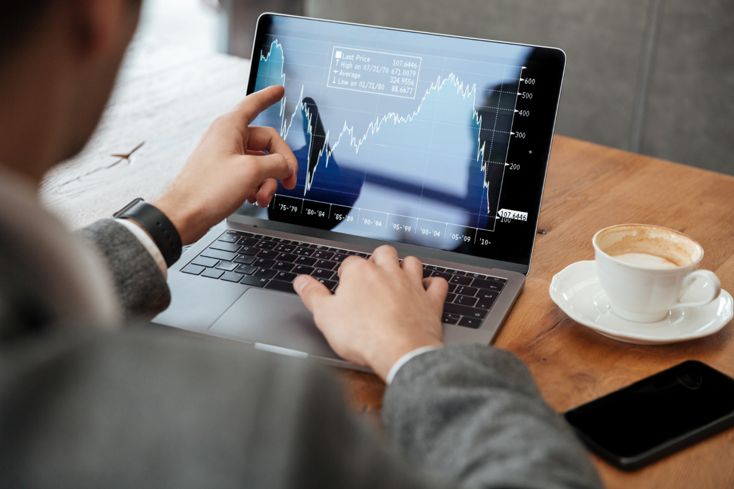 Imagem ilustrativa de dois profissionais conferindo cotações e gráficos em um notebook durante reunião no escritório, em referência à comparação de rentabilidade entre aplicações financeiras