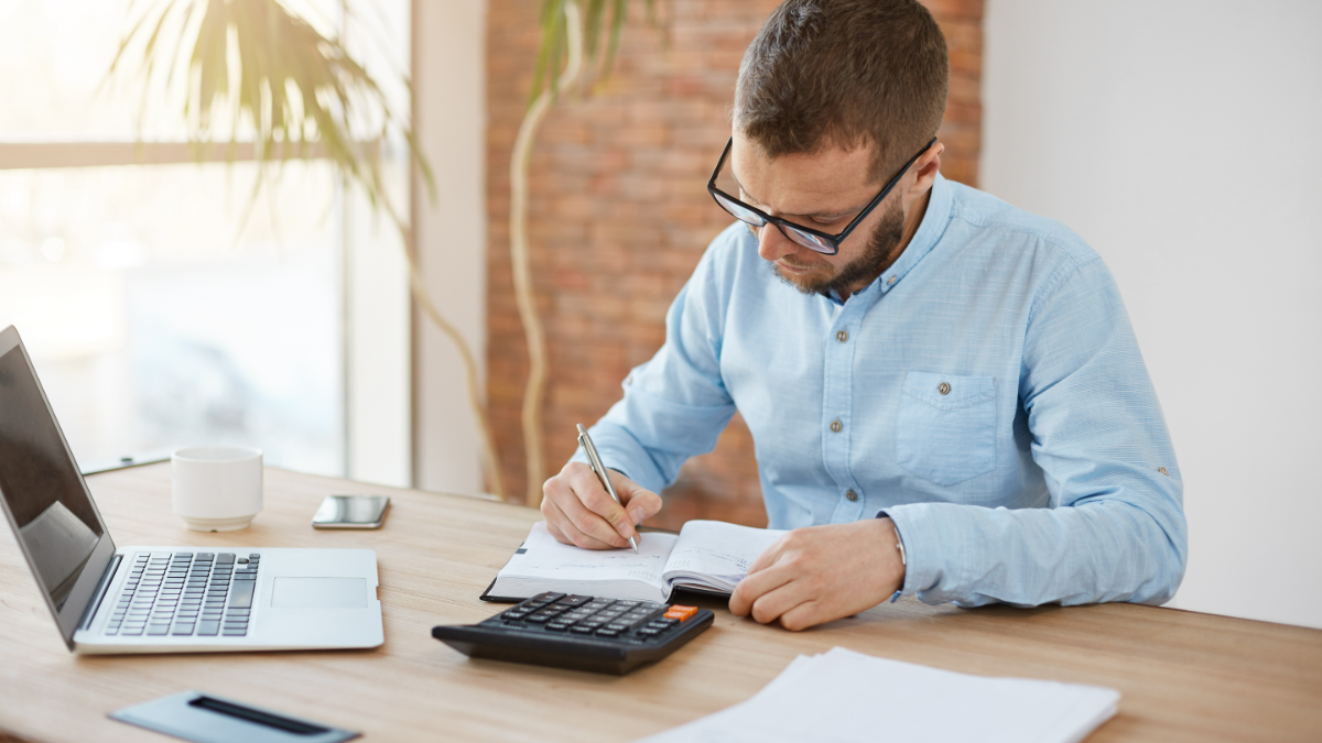 Jovem adulto concentrado em cálculos financeiros no escritório.