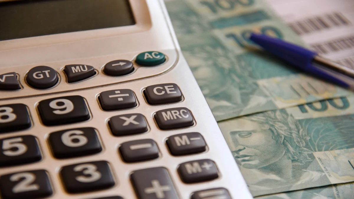 Calculadora e dinheiro representam planejamento financeiro para definir valor mensal de pagamento de dívidas.