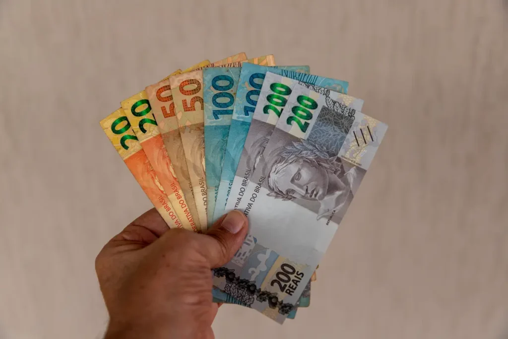 Pessoa segurando cédulas de real, representando a importância de montar uma reserva de emergência em 2026 mesmo com salário curto.